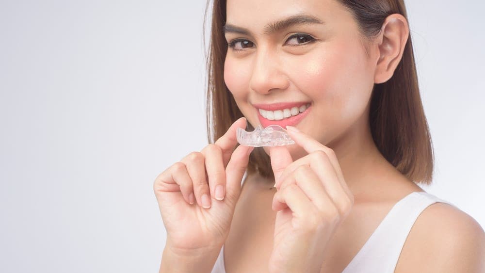 A woman holding a clear aligner tray