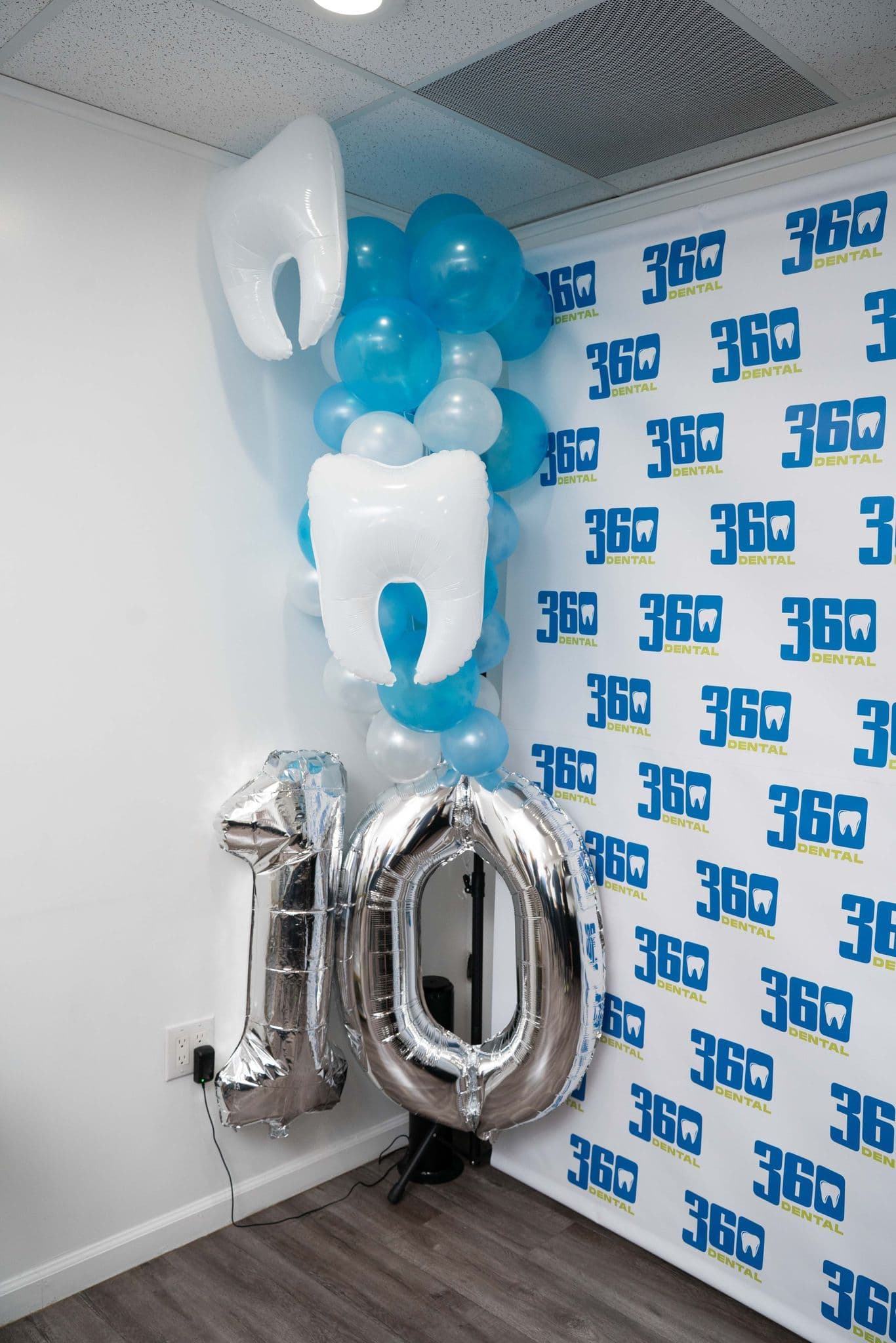 Tooth balloons and a silver number 10 against a 360 Dental backdrop at the practice's tenth anniversary