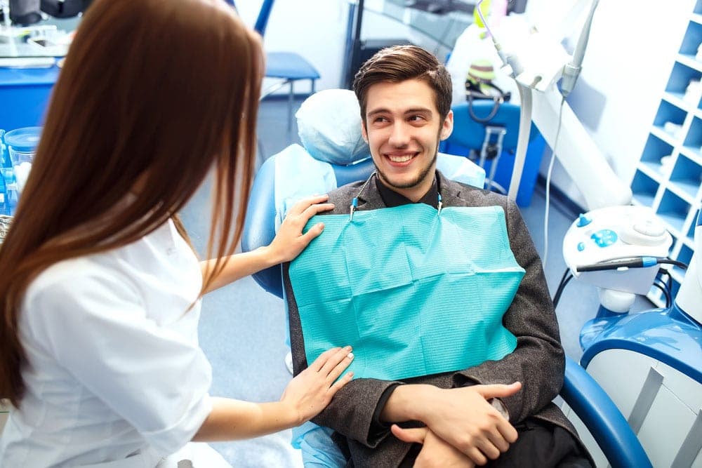 A relaxed patient talking with the dentist beside the chair