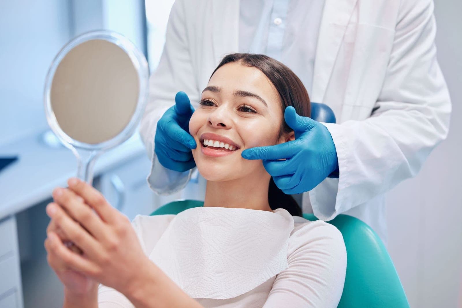 A patient with a hand mirror during a cleaning appointment