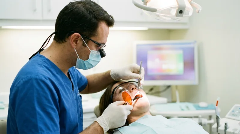 Dentist applying tooth-colored bonding material to a patient's front tooth