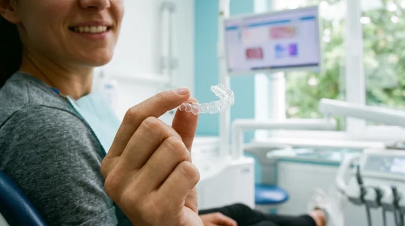 Patient holding a clear Invisalign aligner tray during a dental consultation in Van Nuys