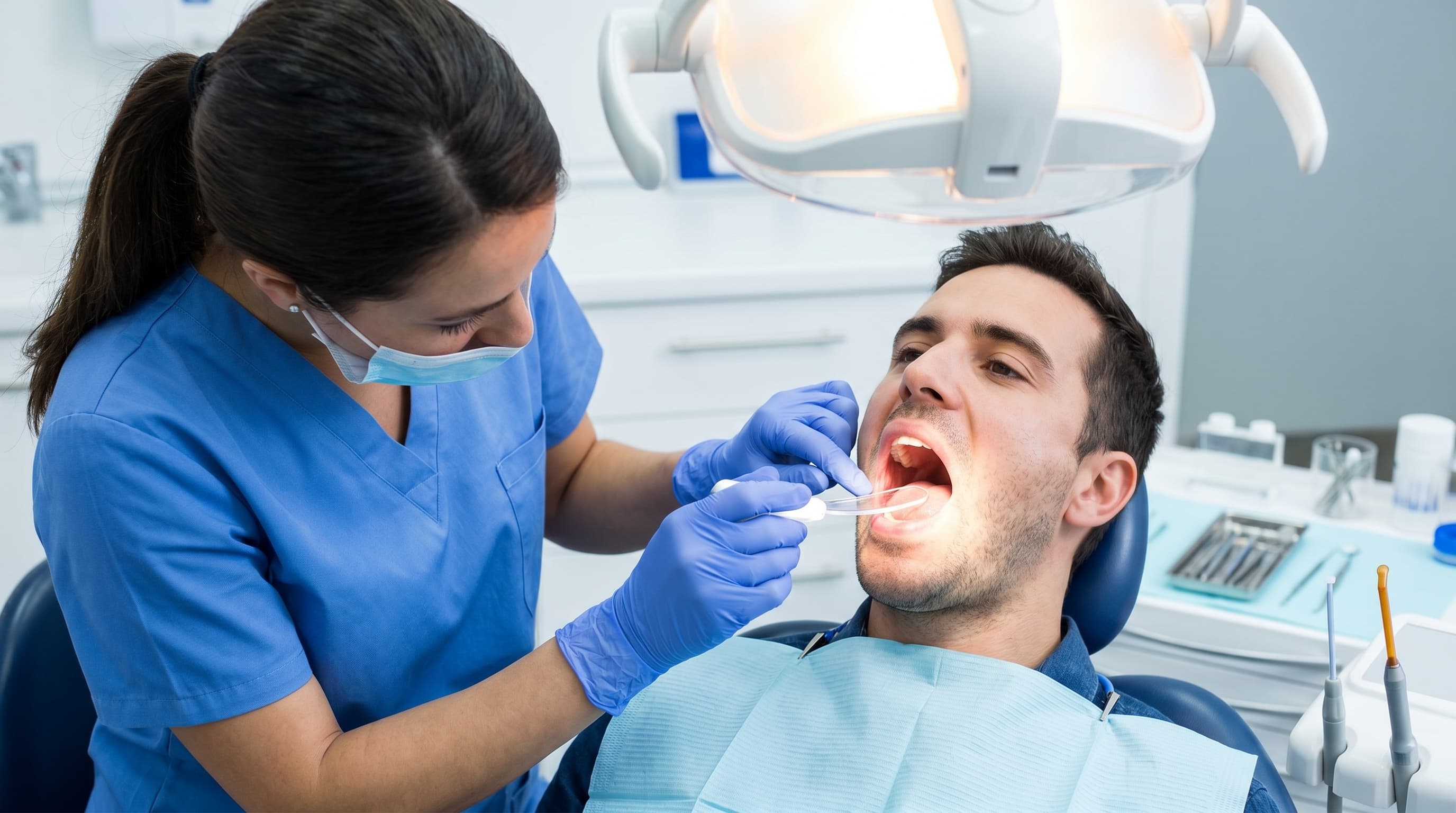 Dentist Examining Patient Mouth with Tongue Depressor Light